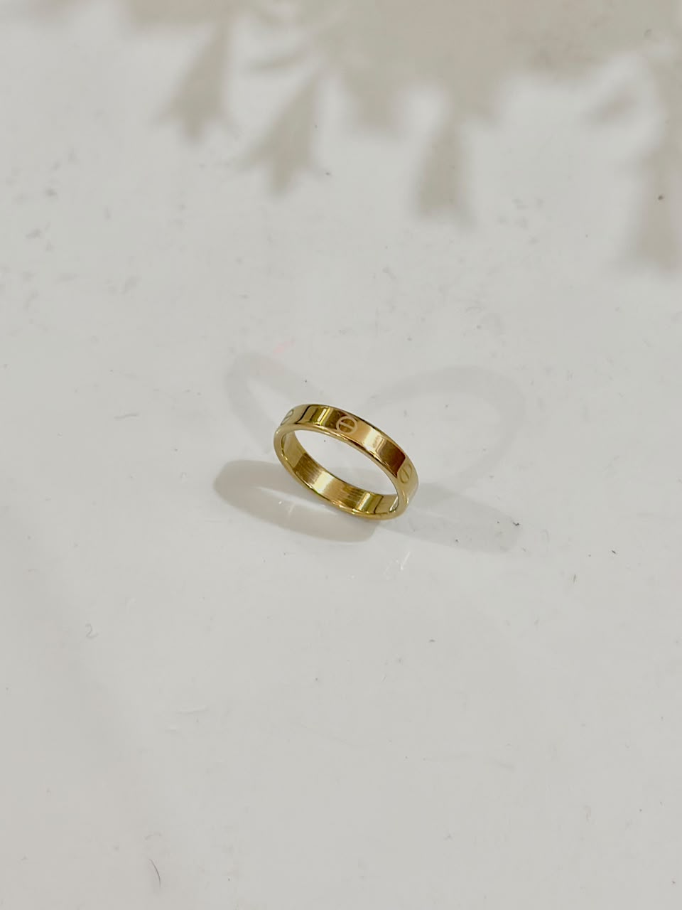 Golden Cartier Style Love Ring by Bloslily, showcasing a sleek band with engraved love motifs on shiny jewelry surface.