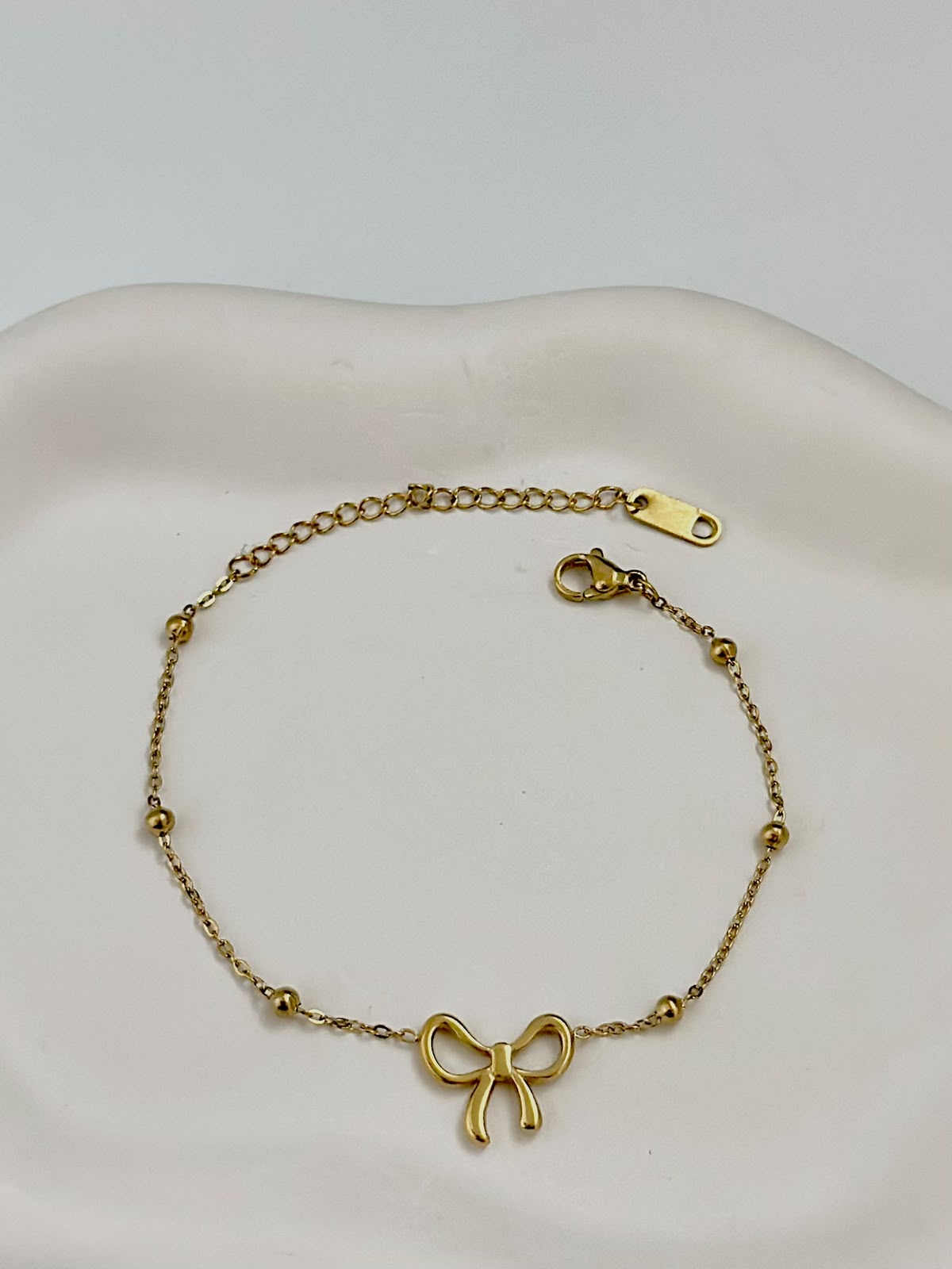 Silver dainty bow charm bracelet by Bloslily featuring a delicate bow design on a sleek jewelry bracelet.