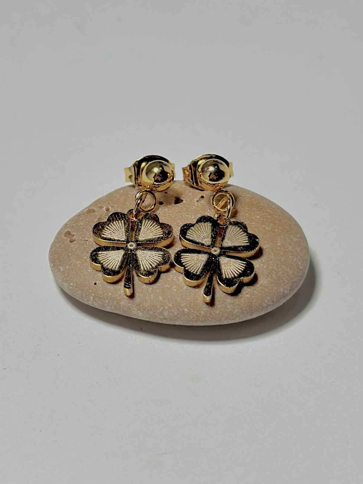 Bloslily textured four-leaf clover drop earrings with detailed leaf design, hanging from hooks in a jewelry display.